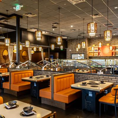 Dining room featuring distinctive orange booths and industrial style pendant lighting.