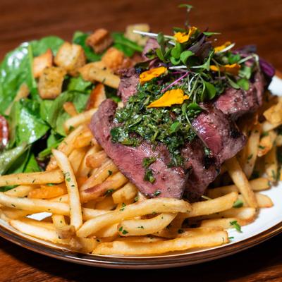 Steak Frites, with spicy chimichurri, chipotle ketchup, mixed greens, and Champagne vinaigrette.