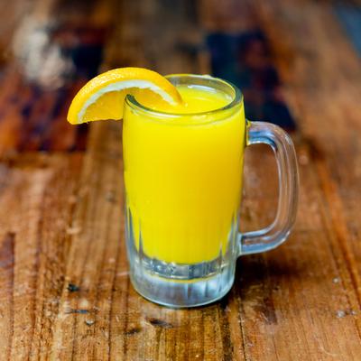 Glass of Orange juice garnished with an orange wedge.