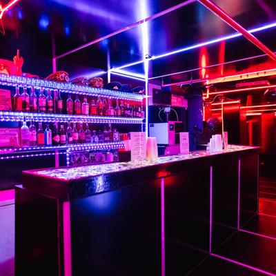 Blue and red lights illuminate a bar, creating a vibrant and inviting ambiance.