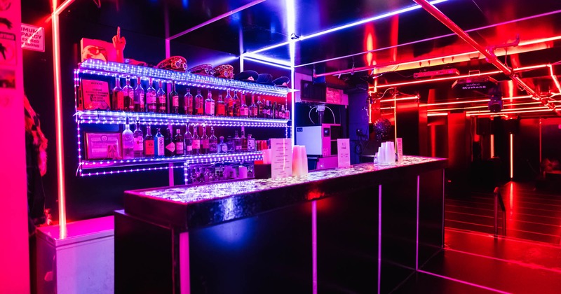 Blue and red lights illuminate a bar, creating a vibrant and inviting ambiance