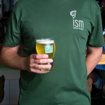 A person wearing a green T-shirt with the logo of ISM Brewing.