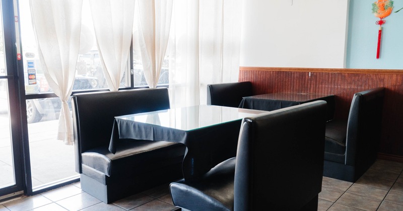 Interior, seating booths with black cloth tables, large shop window with a see-through curtains