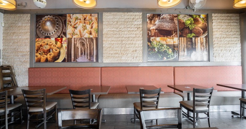 Restaurant interior with tables, chairs, a cushioned bench, and decorative wall panels