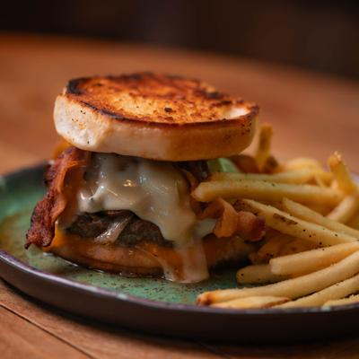 Shroom burger with melted cheese, bacon, and a side of seasoned fries.