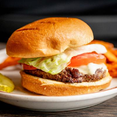 Cheeseburger on a plate with tomato and lettuce.