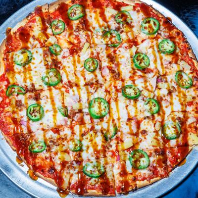 Hawaiian pie topped with diced pineapple, ham, jalapenos and a sauce drizzle.