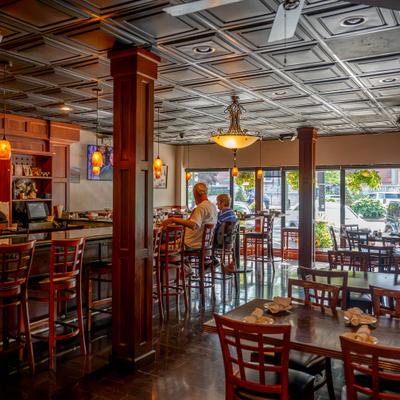 Interior featuring a wooden column, ceiling tiles, and dining tables.