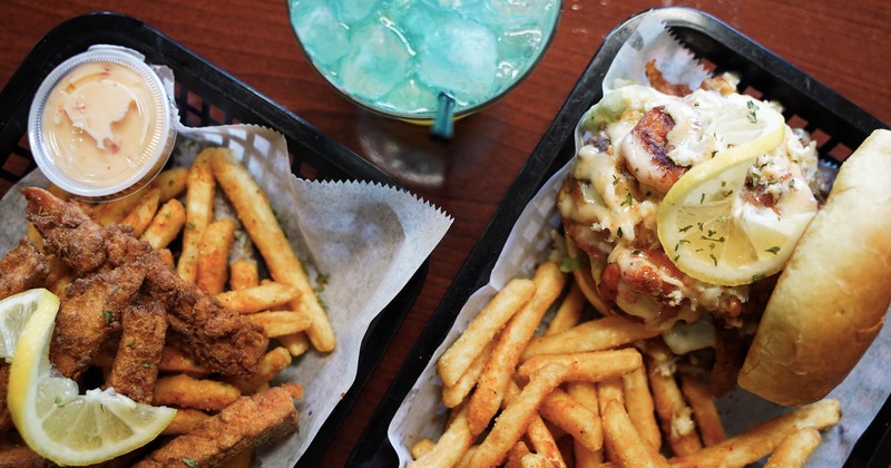 Fried salmon strips and S.I.T.W Burger with fries and a cocktail