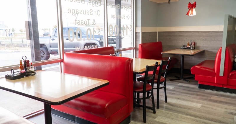Interior of a diner with red booths, wooden tables, and large windows