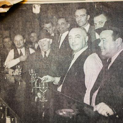 An old black and white photo of people drinking at the bar