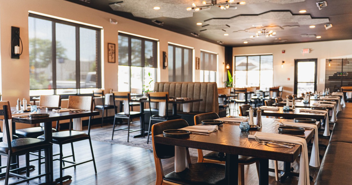 Interior, wooden tables, set with navy blue plates and white napkins, and cushioned booths