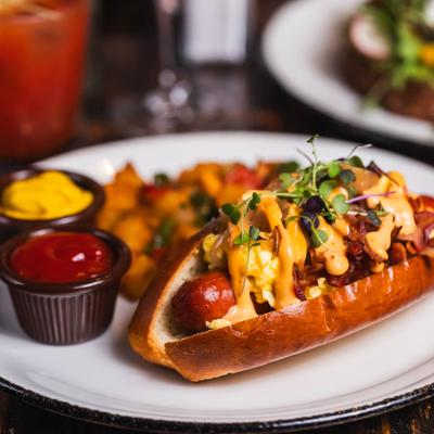 Hot dog loaded with eggs and melted cheese sauce, served with mustard and ketchup.