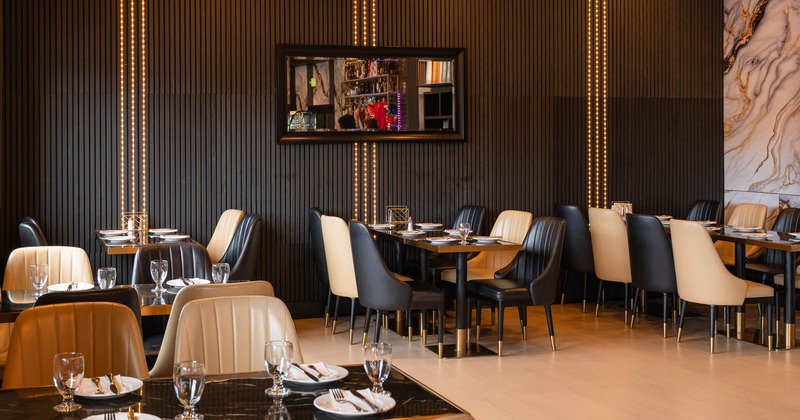 Dining room featuring vertical wood slat walls and minimalist dining chairs in cream and black