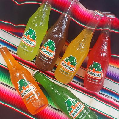 Mexican flavored soda drink bottles displayed on a traditional poncho blanket.