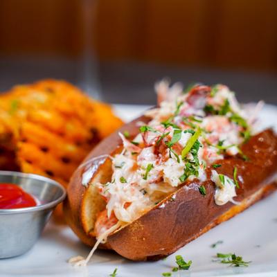 Lobster roll with waffle fries and ketchup.
