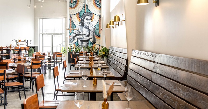 Interior, long wooden banquette benches with tables and chairs, ready for guests