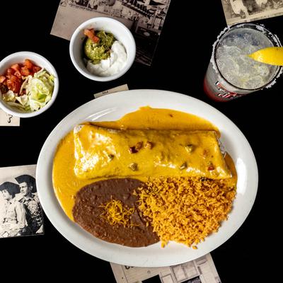 Burrito smothered in cheese sauce, served with rice, and refried beans.