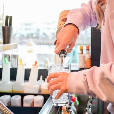 Bartender pouring a drink into a glass filled with ice.