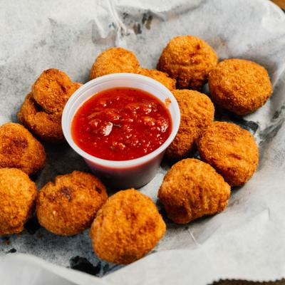 Breaded mushrooms served with marinara sauce on parchment paper.