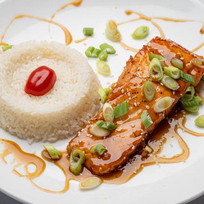 Glazed salmon fillet topped with chopped scallions and served with rice.