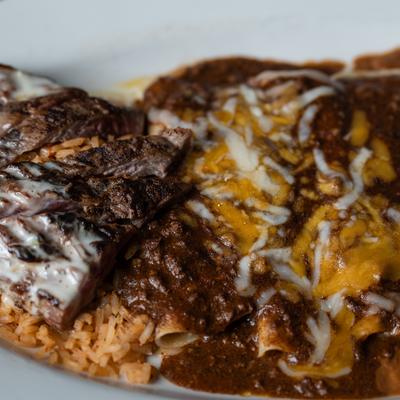 Enchiladas smothered in Mole and cheese sauces, with rice, refried beans, and beef.