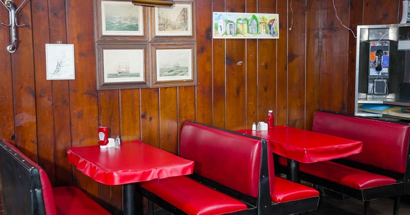 Interior - wooden walls, red booth seating, framed nautical pictures and a vintage payphone