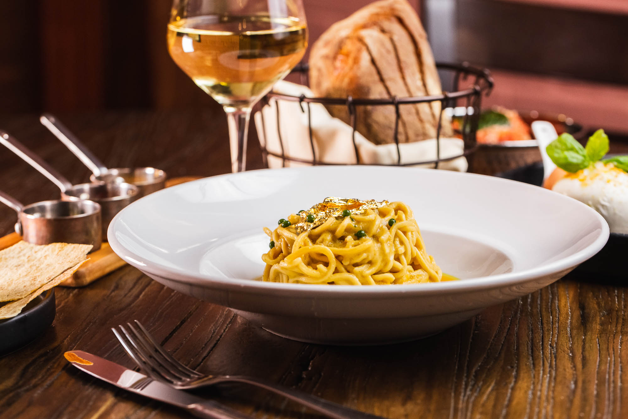 A plate with cheese pepper pasta, accompanied with a glass of white wine