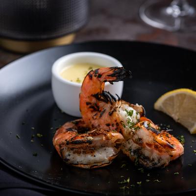 Three grilled shrimp with butter lemon reduction and parsley-lemon garnish.