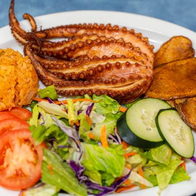 Grilled octopus with rice, roasted potatoes, and fresh salad.