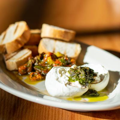 Burrata cheese served with roasted tomatoes, pesto, and toast.