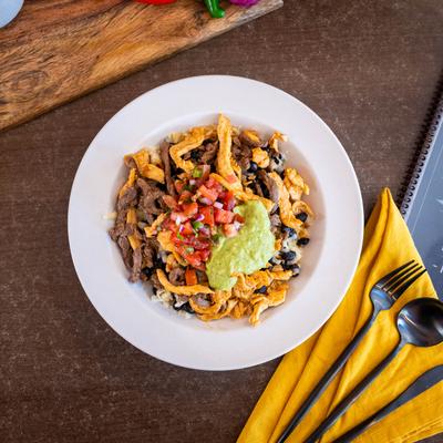 Burrito bowl with chicken and beef, served over rice and black beans, topped with guacamole.