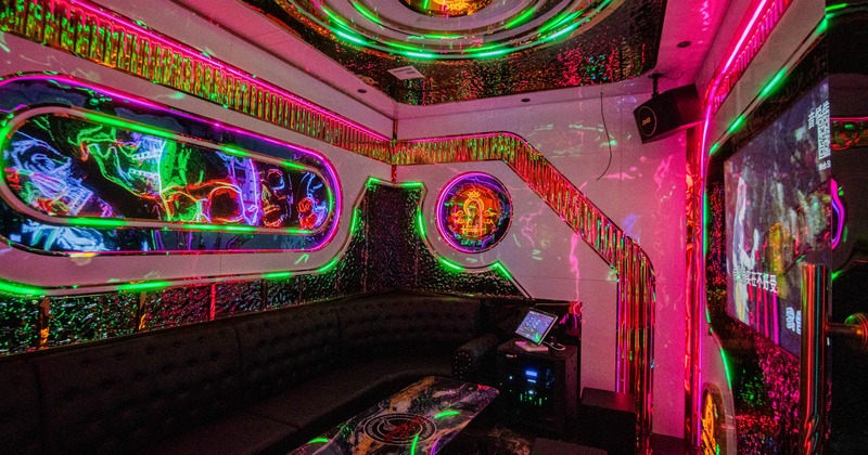 Interior, small karaoke room, neon lighting, sofa, karaoke machine, large TV