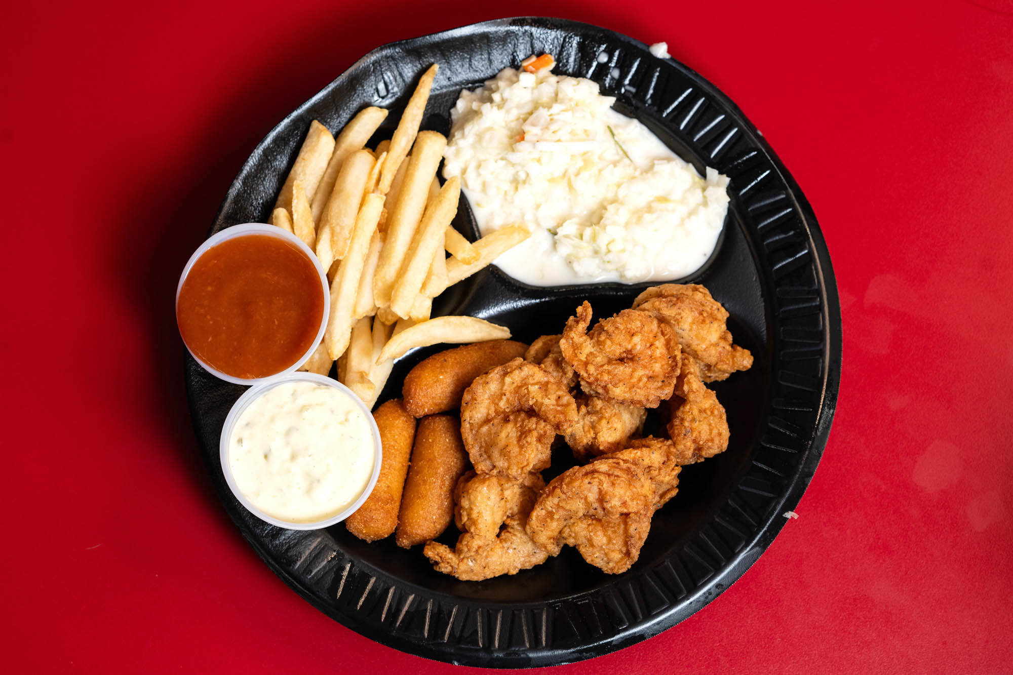 Platter with fried shrimp, hush puppies, fries, mashed potatoes and sauces