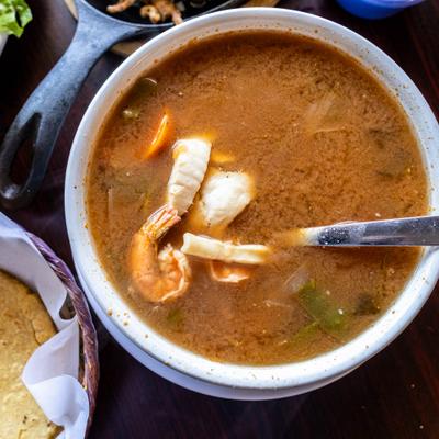 Bowl of seafood soup with tortillas on the side, close-up.