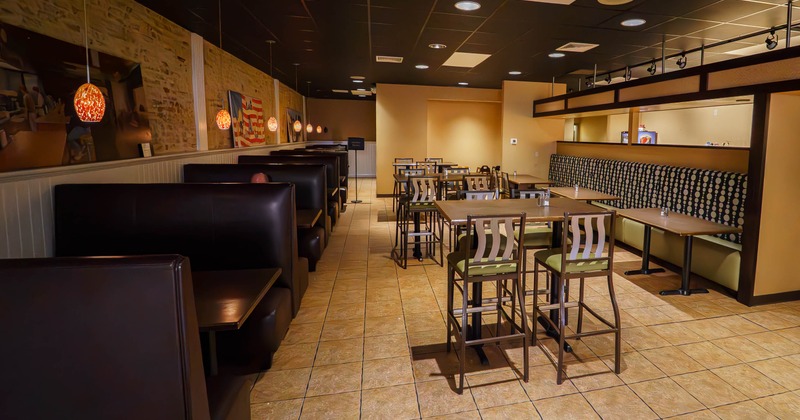 Interior of a modern restaurant with booths, tables, and pendant lights