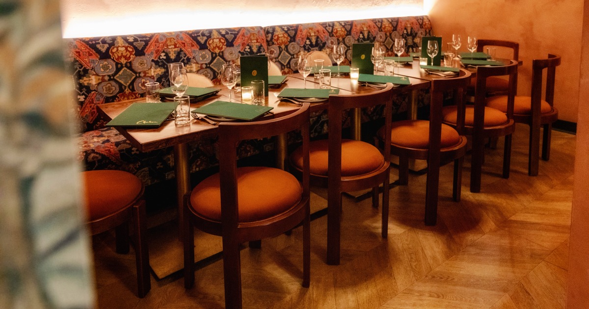 Long restaurant table with patterned banquette seating and red-cushioned chairs