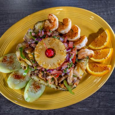 Colorful plate with shrimp, pineapple, meat, and orange slices.