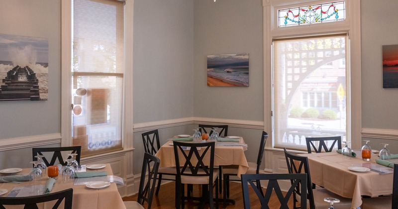 Interior, set dining tables waiting to receive guests, pictures on walls