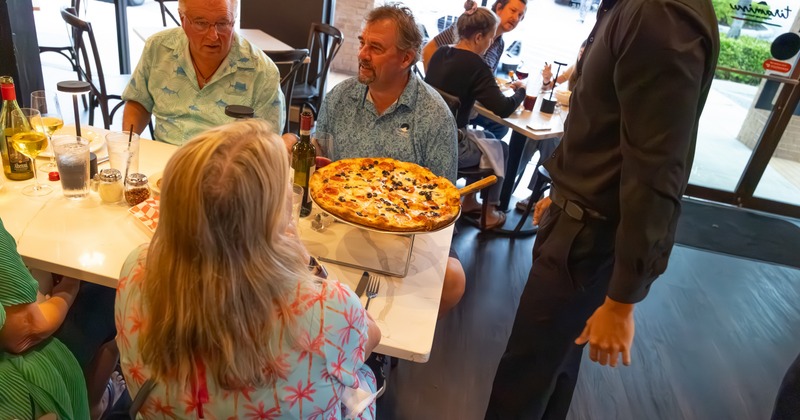 Waiter bringing pizza to family party