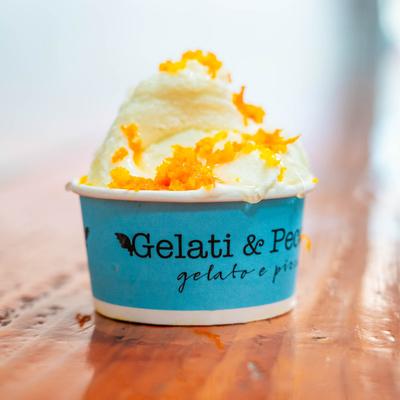 A scoop of olive oil with orange zest gelato in a blue cup.