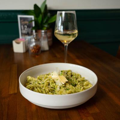 Fusilli in pesto sauce accompanied by a glass of white wine.