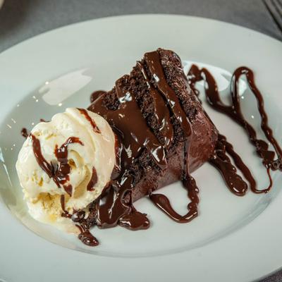 Chocolate cake topped with ice cream and drizzled with chocolate sauce.