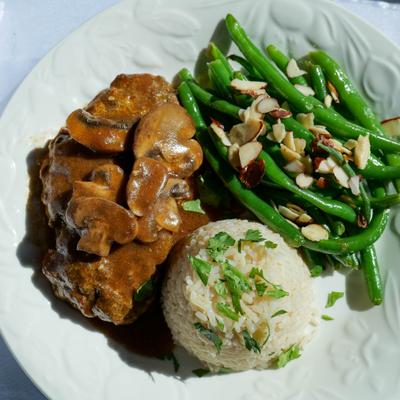 Steak with sides of rice and green beans, top view.