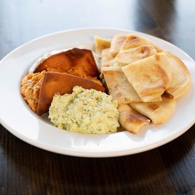 The Trio plate with tzatziki, hummus, and homemade feta spread, served with pita.