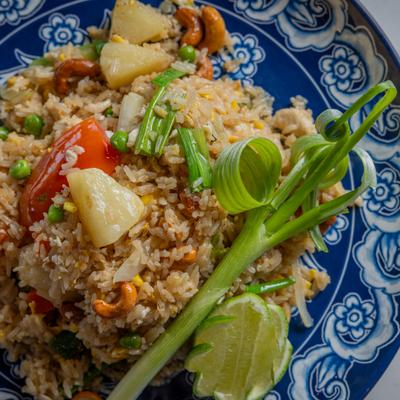 Pineapple fried rice with cashews and vegetables, served on a blue patterned plate.