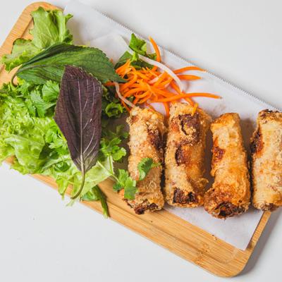 Crispy fried spring rolls served with fresh lettuce, herbs, and shredded carrots.