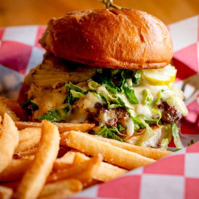 Cheeseburger with lettuce, pickles, melted cheese, and fries.