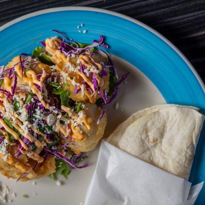 Cauliflower fritters topped with purple cabbage, aioli, and cheese, served with tortillas.