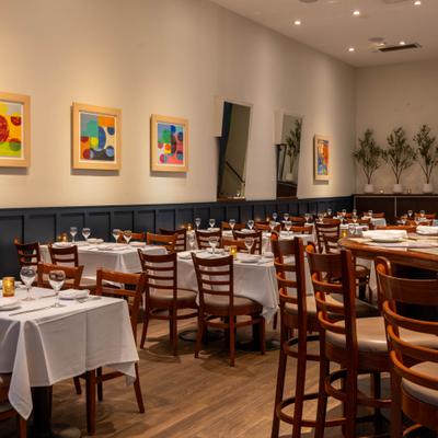 Dining room featuring set tables with white tablecloths and colorful abstract art.